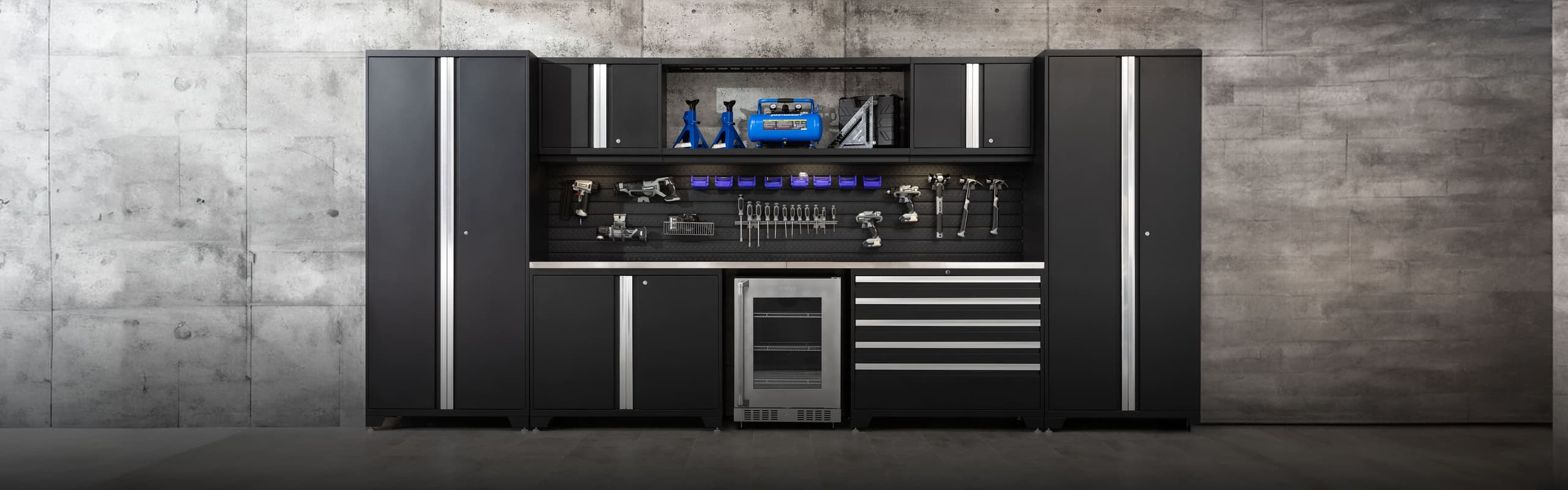 Matte black Pro Series cabinets with a slatwall tool wall, steel worktop and beverage fridge