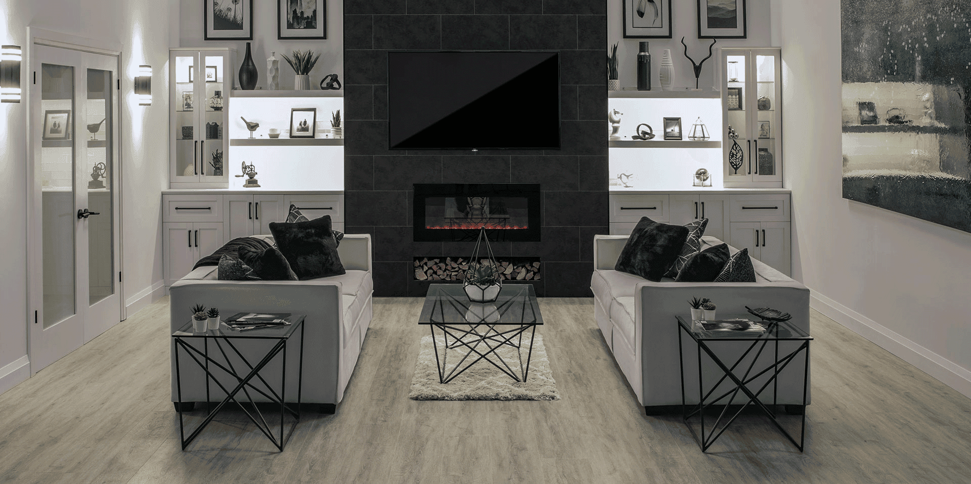 A living room with a wall-mounted TV over a fireplace and gray vinyl plank flooring