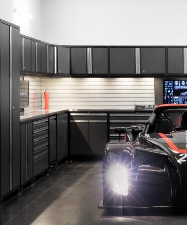 A race car parked in a well-lit garage, showcasing newageproducts garage cabinets in the background.