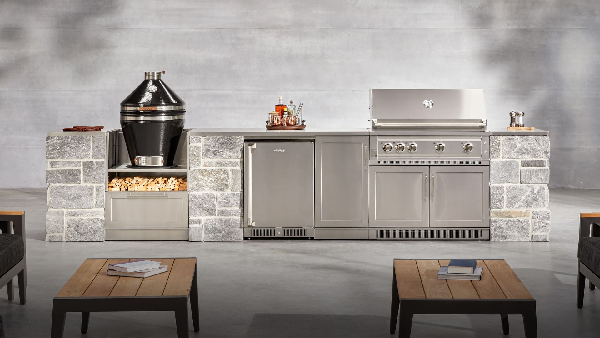 NewAge outdoor kitchen with stone-clad cabinet surrounds, a kamado grill above a firewood store, outdoor fridge and built-in gas grill
