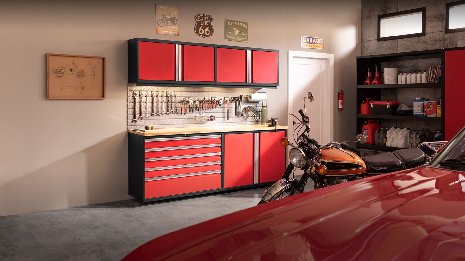 NewAge grey garage cabinets with a stainless-top workbench, tool drawers, wall cabinets and an overhead rack holding tires