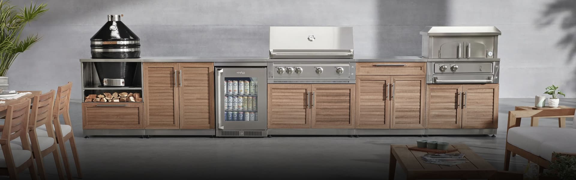Outdoor kitchen with louvered wood-look cabinets, built-in gas grill, kamado charcoal grill, pizza oven and beverage fridge on a patio