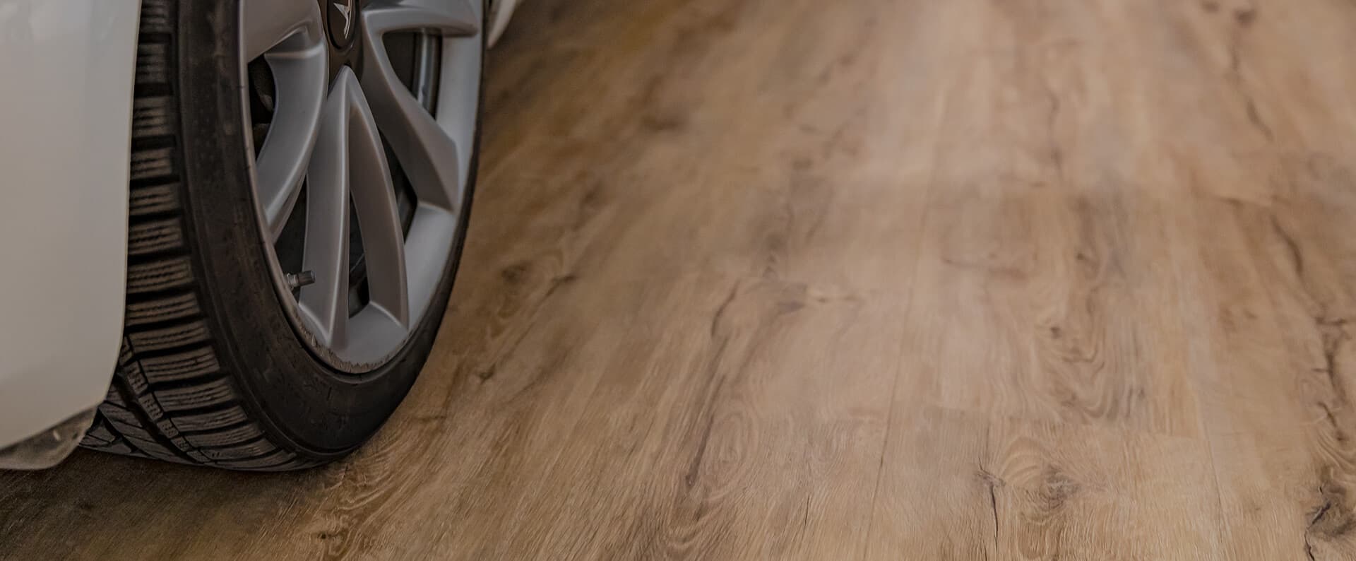 Car tire parked on wood-look garage floor, demonstrating the flooring's durability