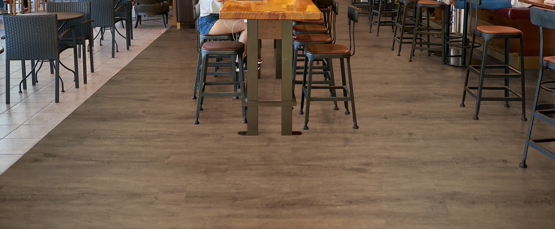 Commercial restaurant seating area with wood-look flooring and bar stools