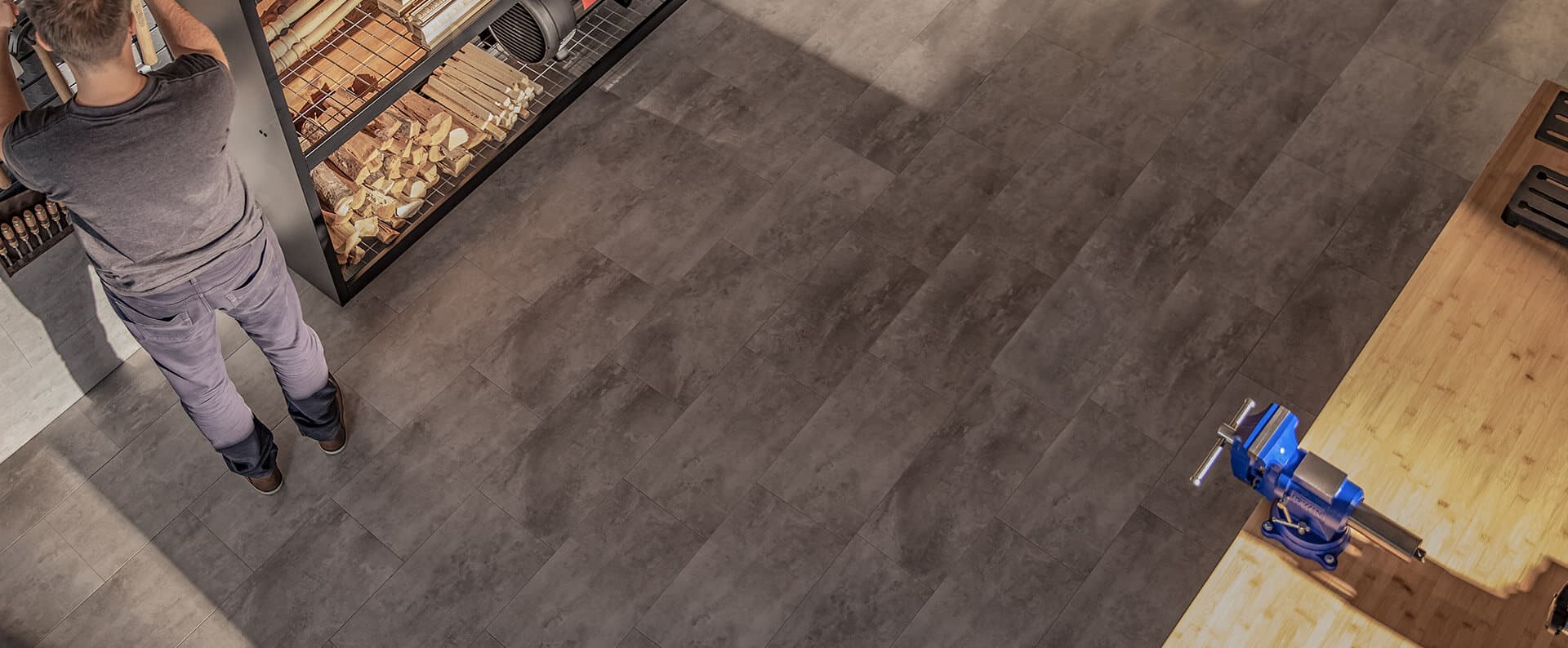 Workshop from above: two-tone gray vinyl tile flooring, a workbench with a vise, shelving