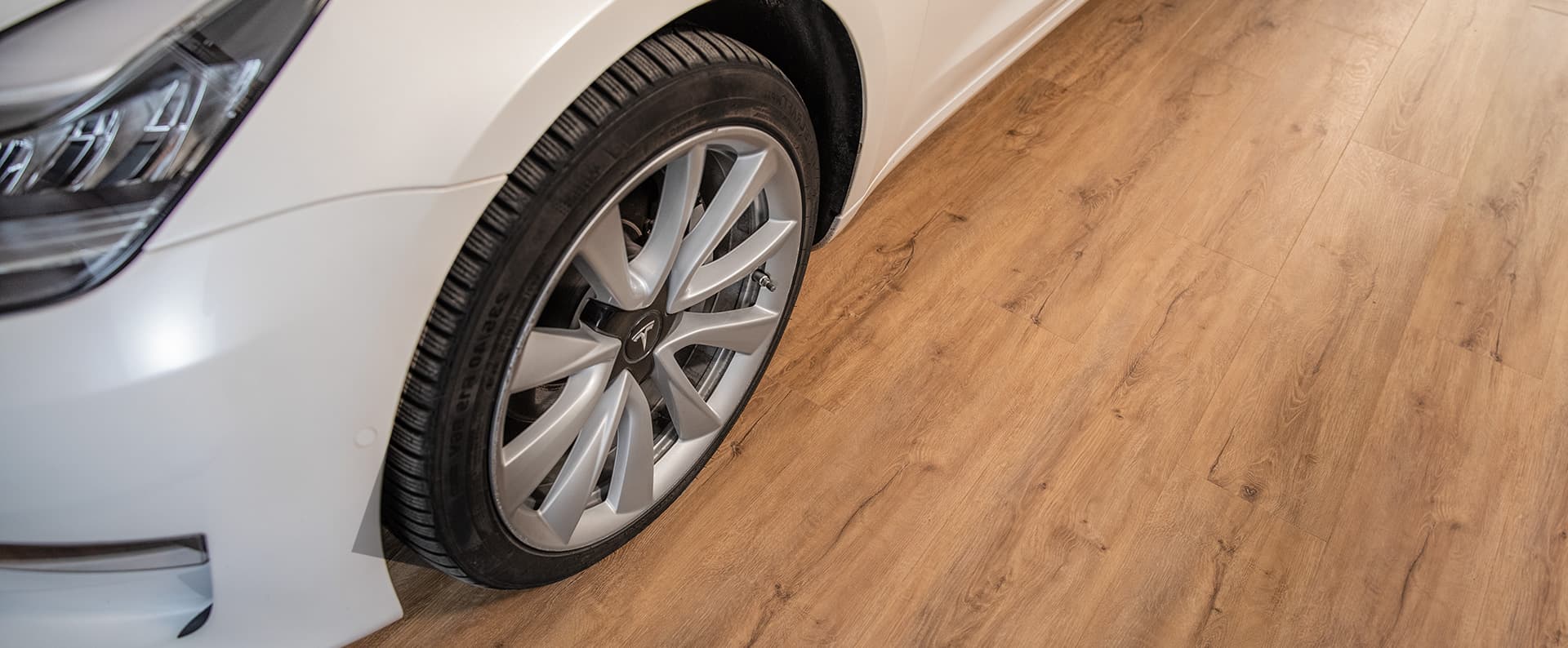 Close-up of a car wheel next to wood-look luxury vinyl plank flooring