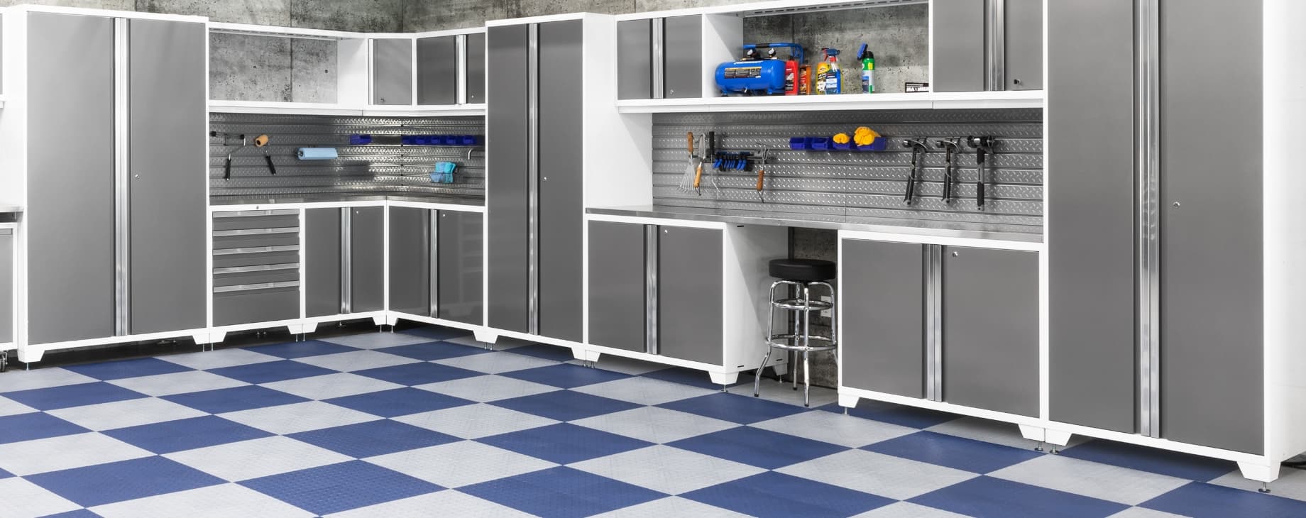 White cabinets and a steel pegboard tool wall on blue and white checkerboard floor tiles