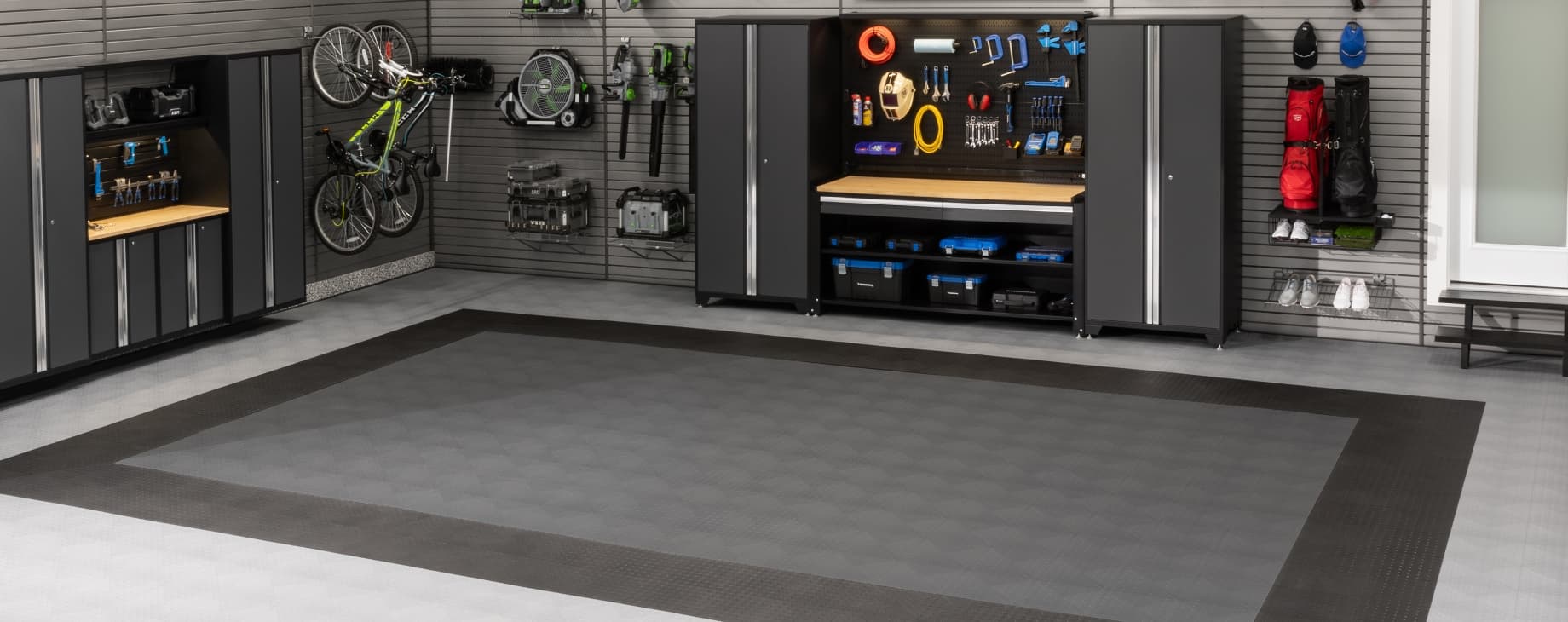 Dark gray cabinets and pegboard beside a wall-mounted bike, gray tiles with a dark border