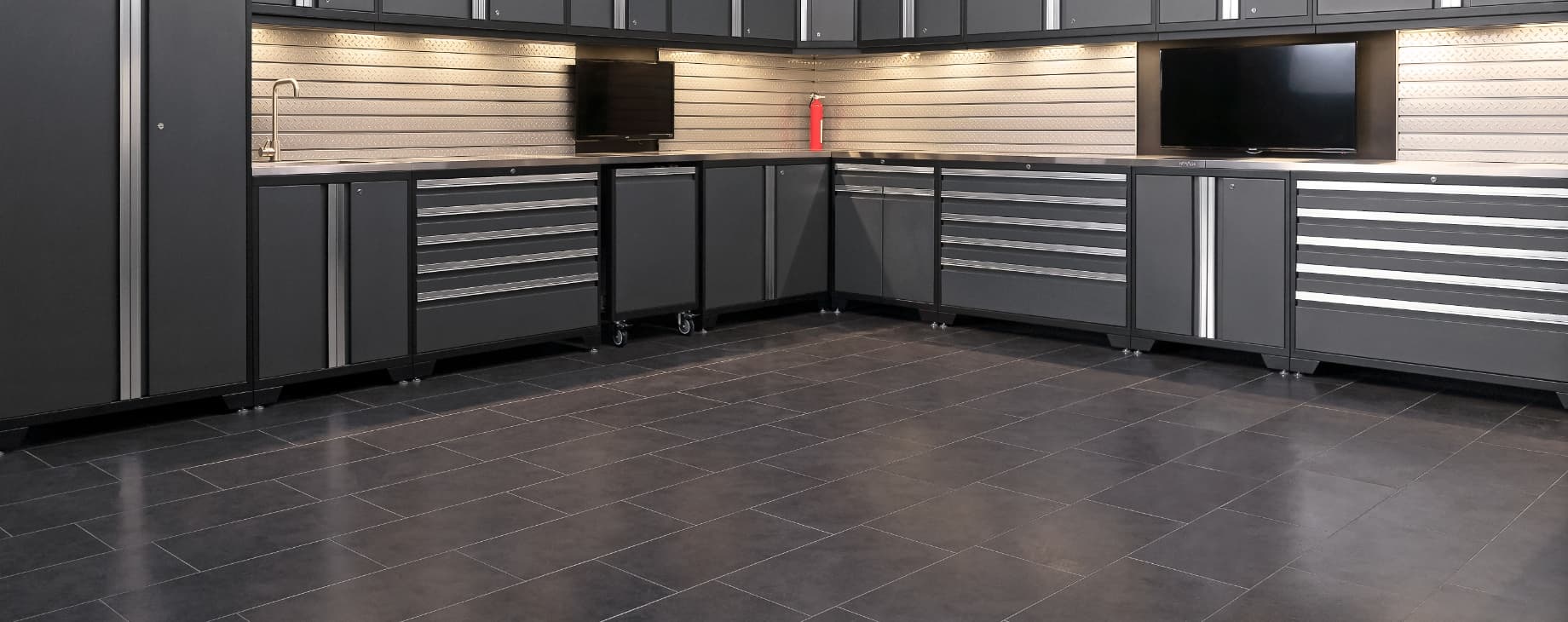 Dark gray floor tiles in a kitchenette setup with gray cabinets, a sink and wall TVs