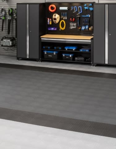 Dark gray cabinets and pegboard beside a wall-mounted bike, gray tiles with a dark border