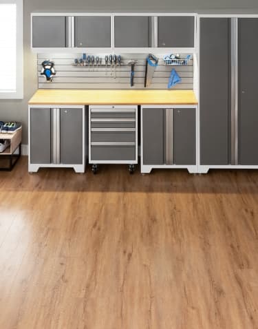 Wood-look vinyl plank flooring in an entryway with gray cabinets and a shoe bench