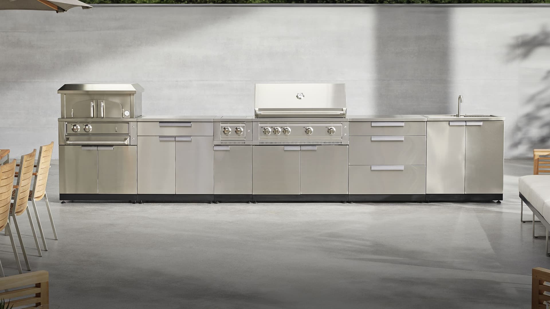 NewAge outdoor kitchen with stone-clad surrounds, a kamado grill and built-in gas grill