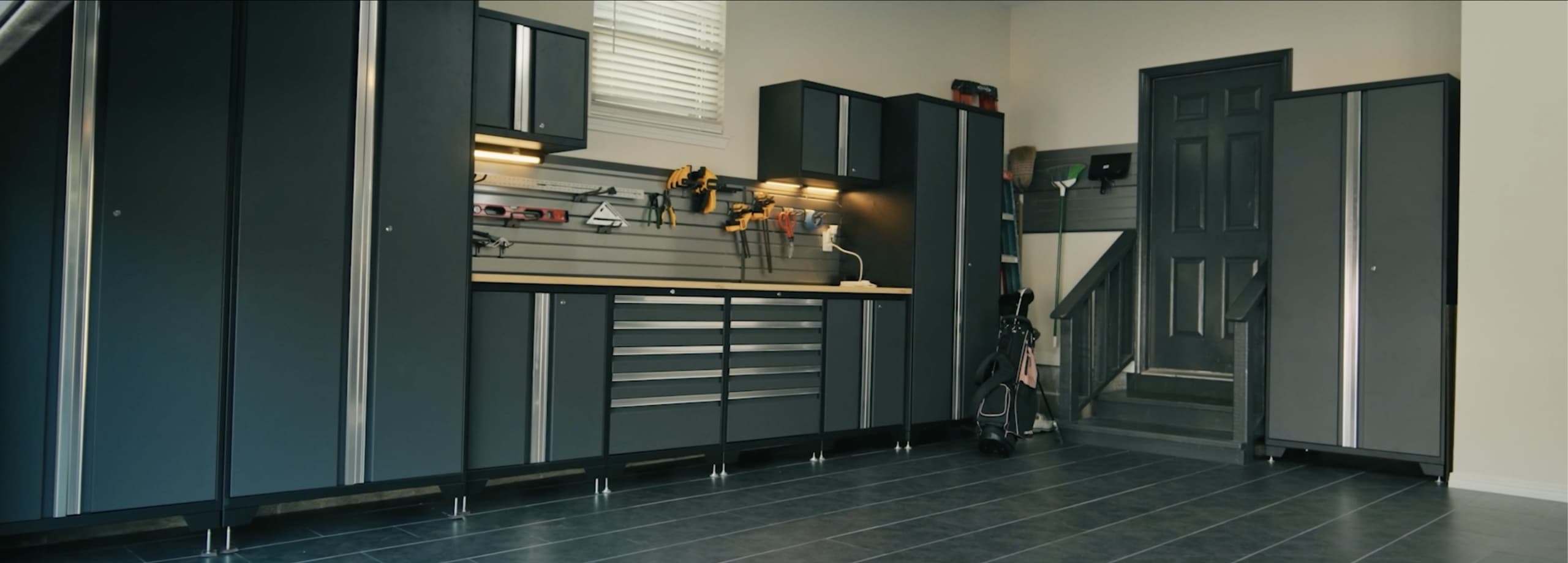 NewAge matte black outdoor kitchen run with a built-in gas grill, outdoor fridge and pizza oven
