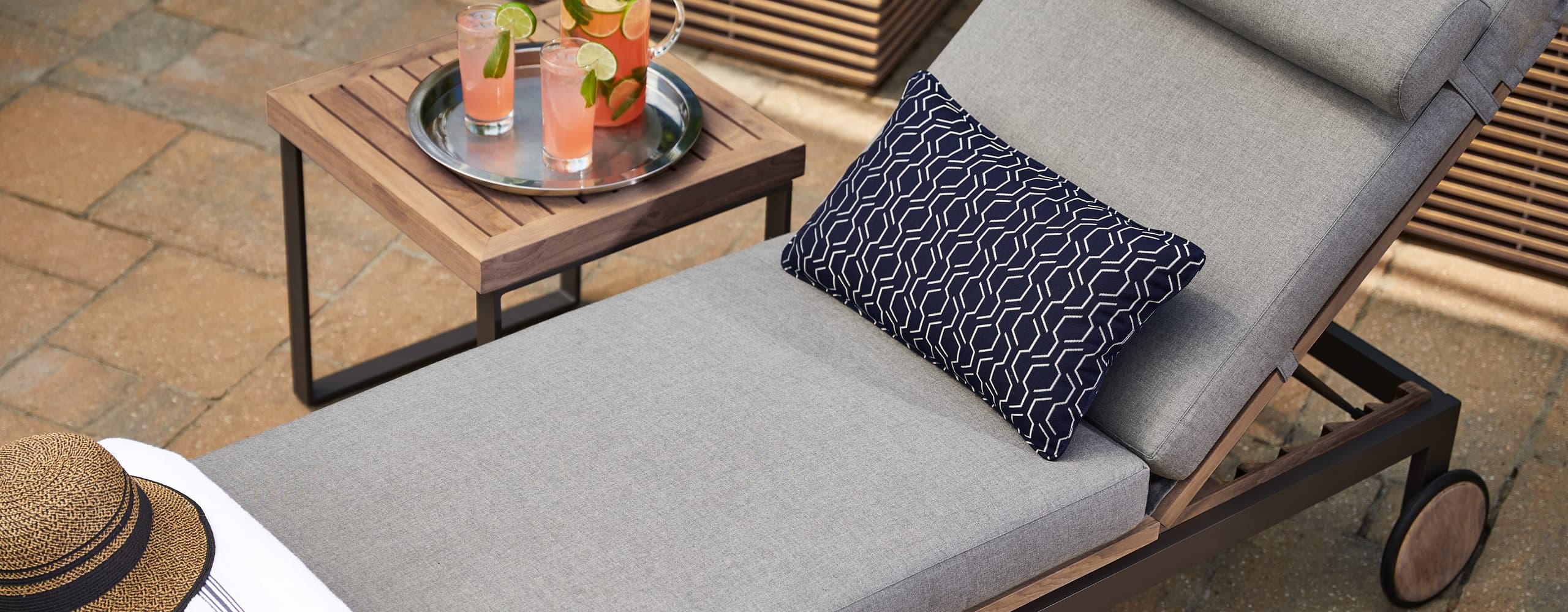 Close-up of a chaise lounge cushion and pillow beside a drink tray
