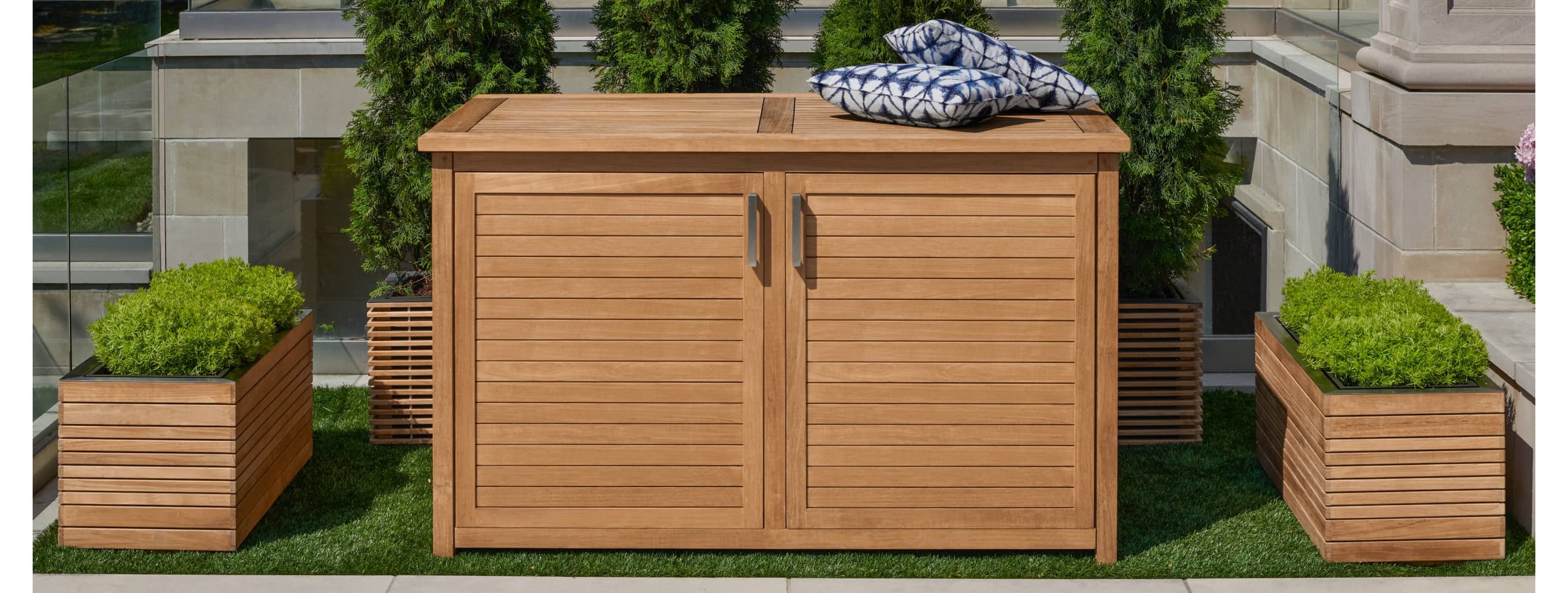 Teak deck box on a patio beside outdoor lounge furniture