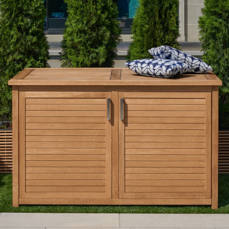 Teak deck box on a patio beside outdoor lounge furniture